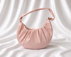 Blush pink crescent shoulder bag with soft pleated detailing and adjustable knotted strap by Eisela.