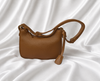 Eisela caramel brown pebbled crossbody bag with adjustable shoulder strap and gold-tone hardware.