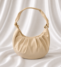 Ivory crescent shoulder bag with soft gathered detailing, adjustable knotted strap, and gold-tone hardware by Eisela.