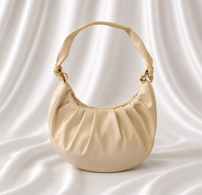 Ivory crescent shoulder bag with soft gathered detailing, adjustable knotted strap, and gold-tone hardware by Eisela.