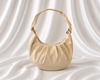 Ivory crescent shoulder bag with soft gathered detailing, adjustable knotted strap, and gold-tone hardware by Eisela.