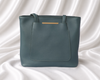 Sage green structured tote bag with front slip pocket, gold-tone accent, and dual shoulder handles by Eisela.